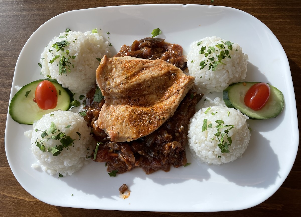 Grilovaný kurací steak s ryžou a paradajkovou omáčkou na bielom tanieri
