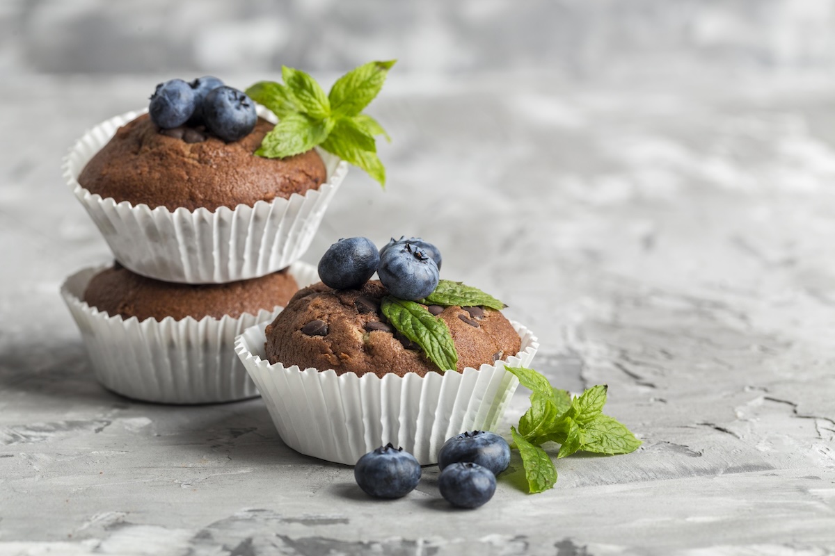 Kakaové muffiny s čučoriedkami a mätou na svetlom pozadí
