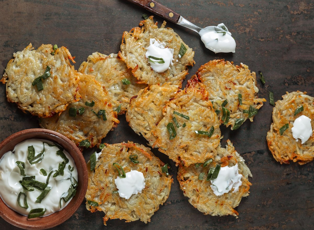 Chrumkavé domáce zemiakové placky so smotanovým dipom a bylinkami podávané na drevenom stole