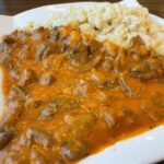 Hlivový perkelt na paprike s haluškami na bielom tanieri