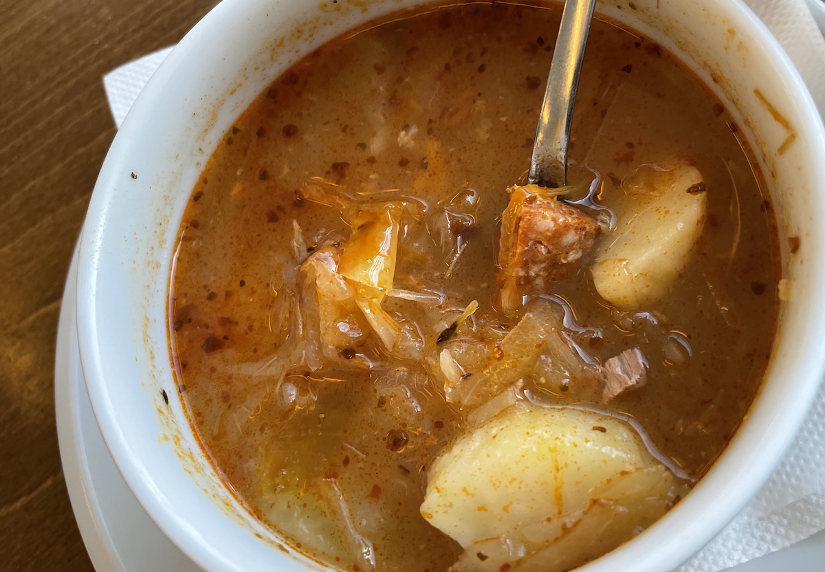 Kapustová polievka s klobásou a zemiakmi v bielej miske, hustá domáca polievka s kúskami mäsa a kapusty