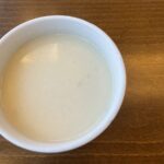 Krémová karfiolová polievka v bielej miske na drevenom stole