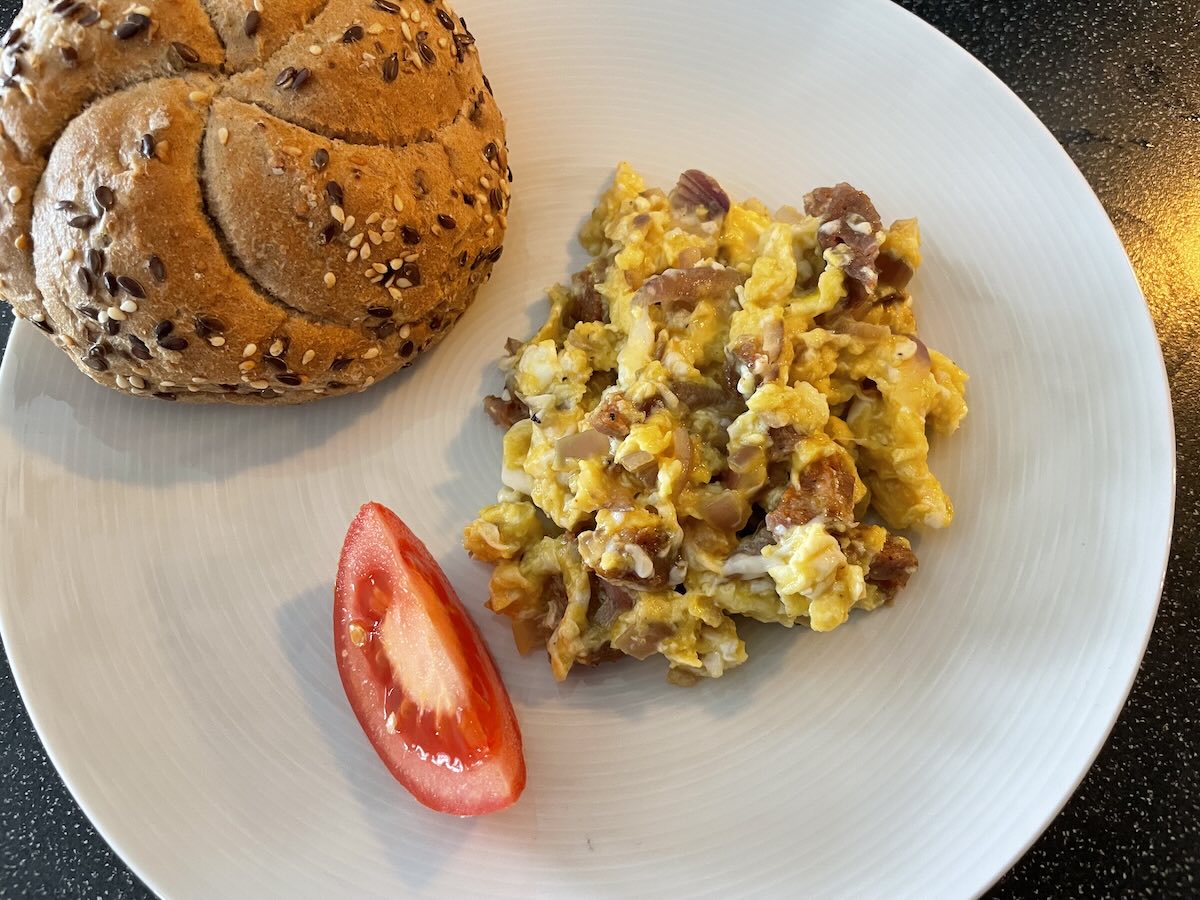 Miešané vajíčka s klobásou podávané s čerstvou žemľou a paradajkou