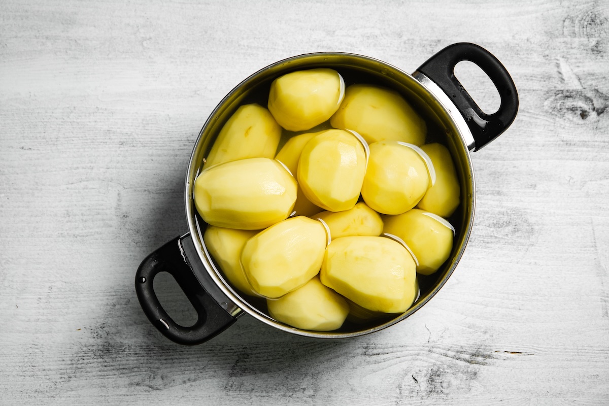 Ošúpané zemiaky v hrnci zaliate studenou vodou pred varením