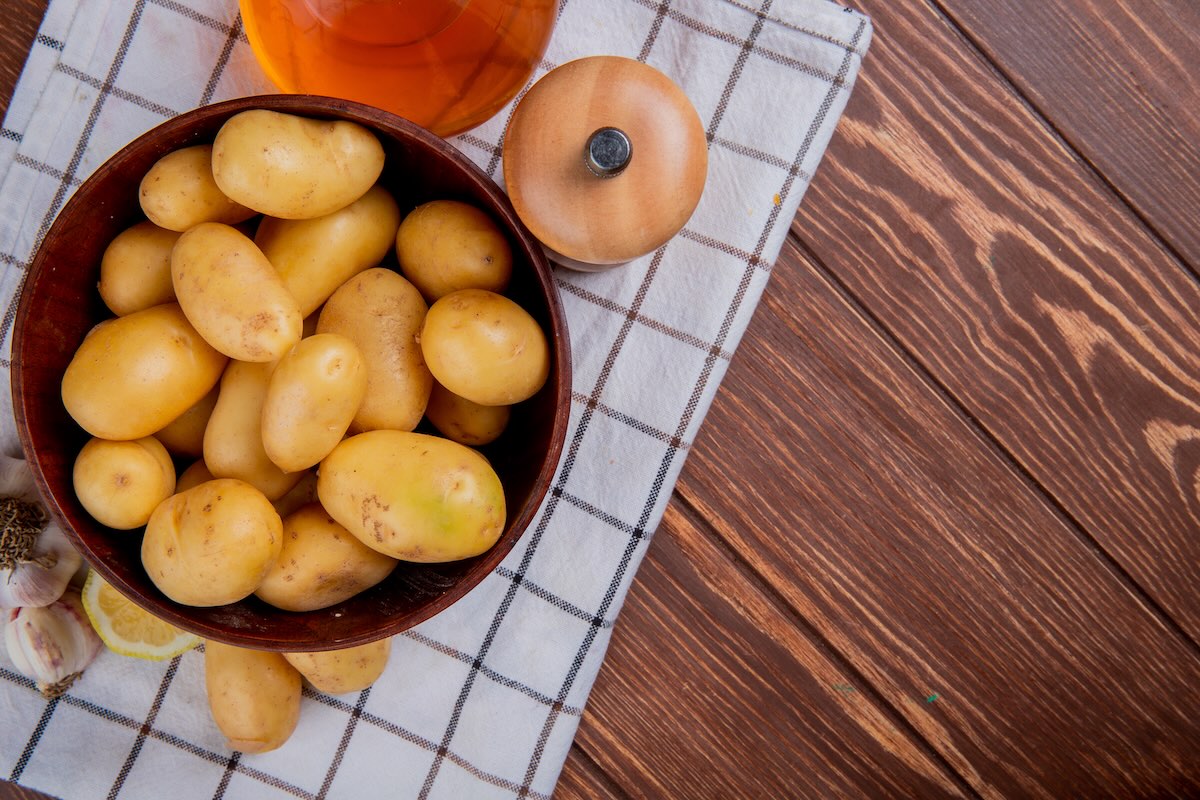Zemiaky v šupke pripravené na varenie v miske na drevenom stole