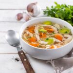 Číry domáci kurací vývar s rezancami, mrkvou, zeleninou a kúskami mäsa podávaný v bielom tanieri