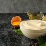 Domáca majonéza v sklenenej miske s vaječným žĺtkom, olejom, citrónom a horčicou