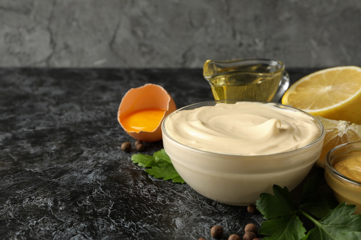 Domáca majonéza v sklenenej miske s vaječným žĺtkom, olejom, citrónom a horčicou