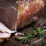 Nakrájané údené mäso na drevenej doske s rozmarínom a korením