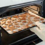 Plech s vianočnými medovníkmi a sušienkami pri vkladaní do rúry na pečenie