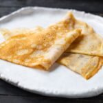 Tenké zlatohnedé palacinkyložené na bielom keramickom tanieri