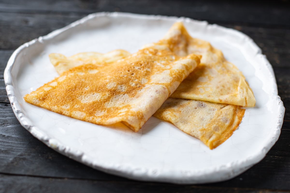 Tenké zlatohnedé palacinkyložené na bielom keramickom tanieri