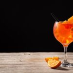 Glass of aperol spritz cocktail on wooden table