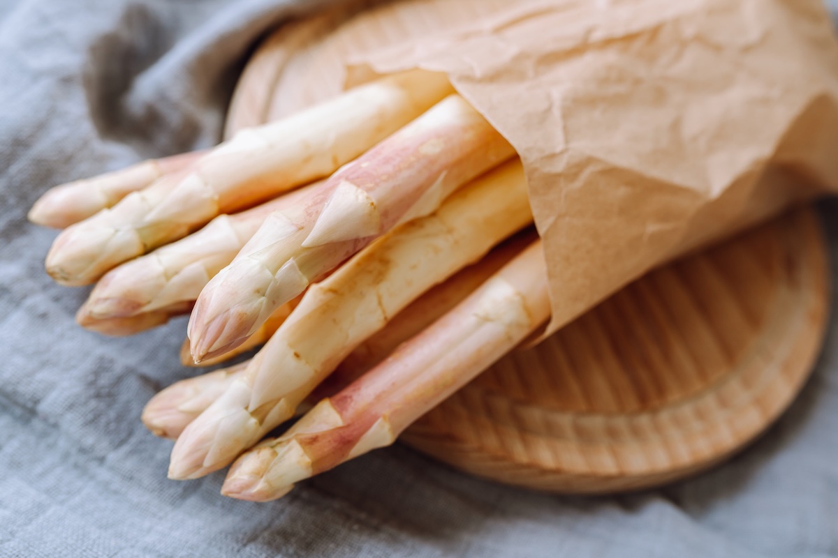 Čerstvá biela špargľa pripravená na spracovanie na drevenom stole