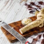 Čerstvý chren na drevenej doske so strúhadlom a nastrúhaným chrenom v miske