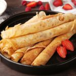 Domáce palacinky na tanieri s jahodami a práškovým cukrom