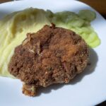 Jednoduchý mletý rezeň s pyré a uhorkový šalátom na bielom tanieri