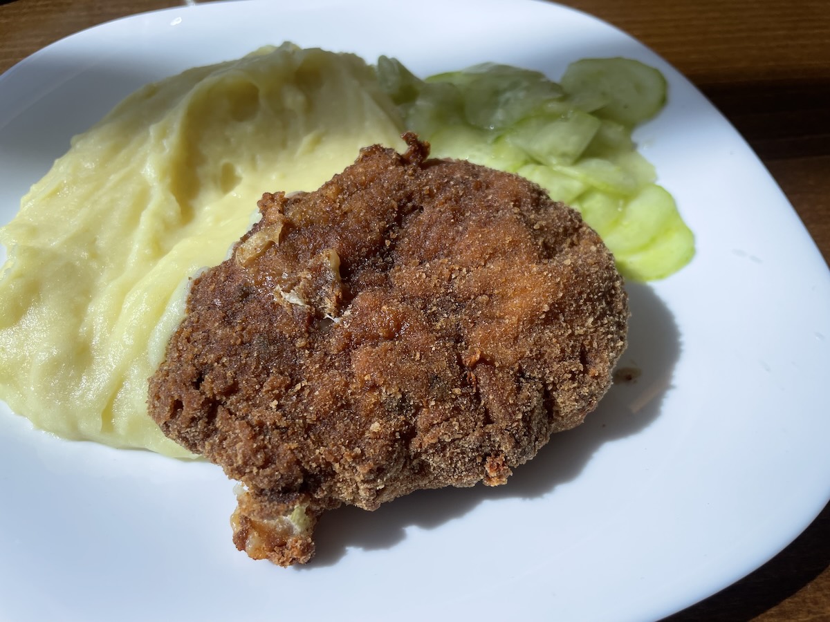 Jednoduchý mletý rezeň s pyré a uhorkový šalátom na bielom tanieri