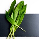 Čerstvé listy medvedieho cesnaku na čiernej bridlicovej doske