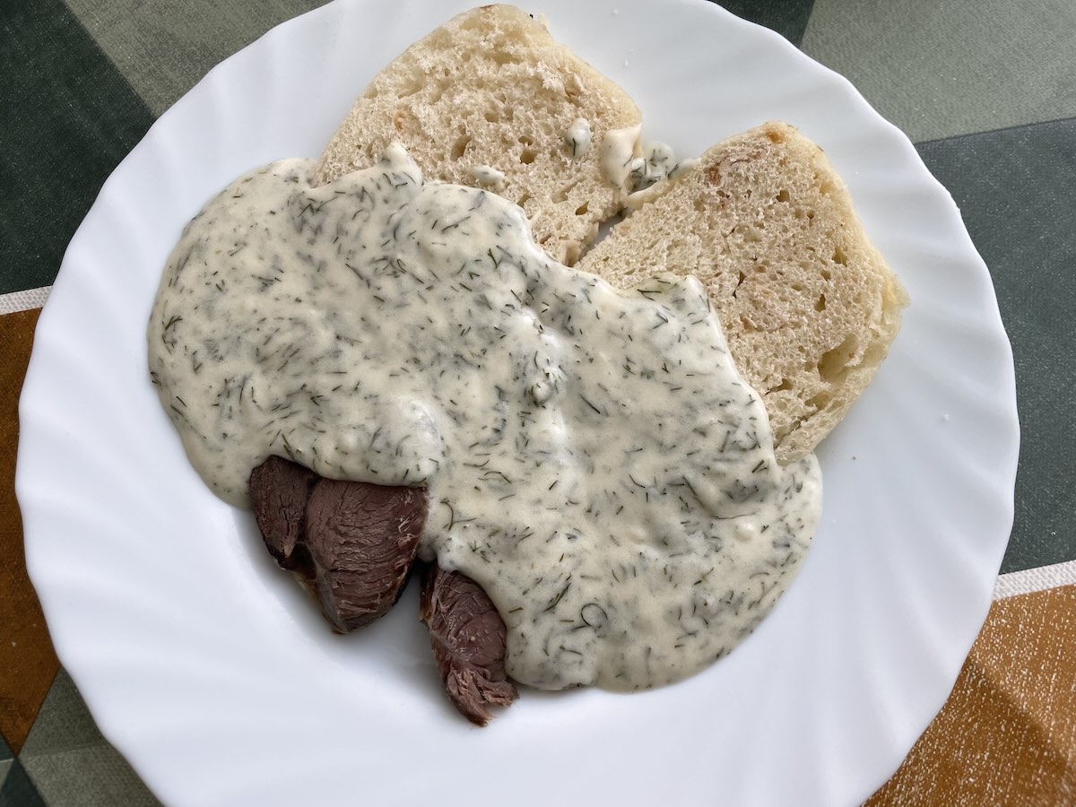 Kôprová omáčka s hovädzím mäsom a knedľou na bielom tanieri