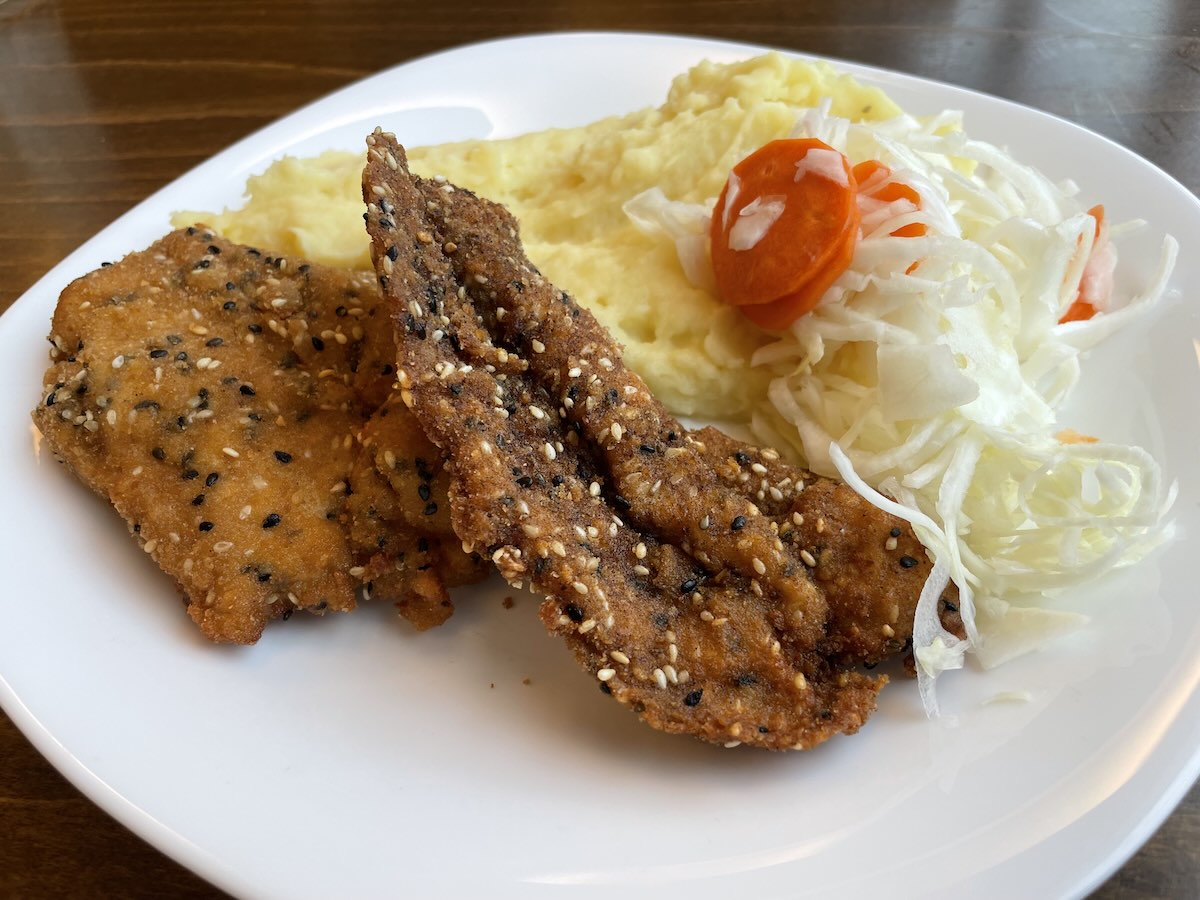 Kurací rezeň v sezame so zemiakovou kašou a kapustovým šalátom na tanieri