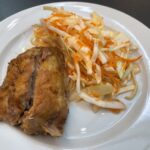 Pečené morčacie stehno podávané s kapustovým šalátom na bielom tanieri