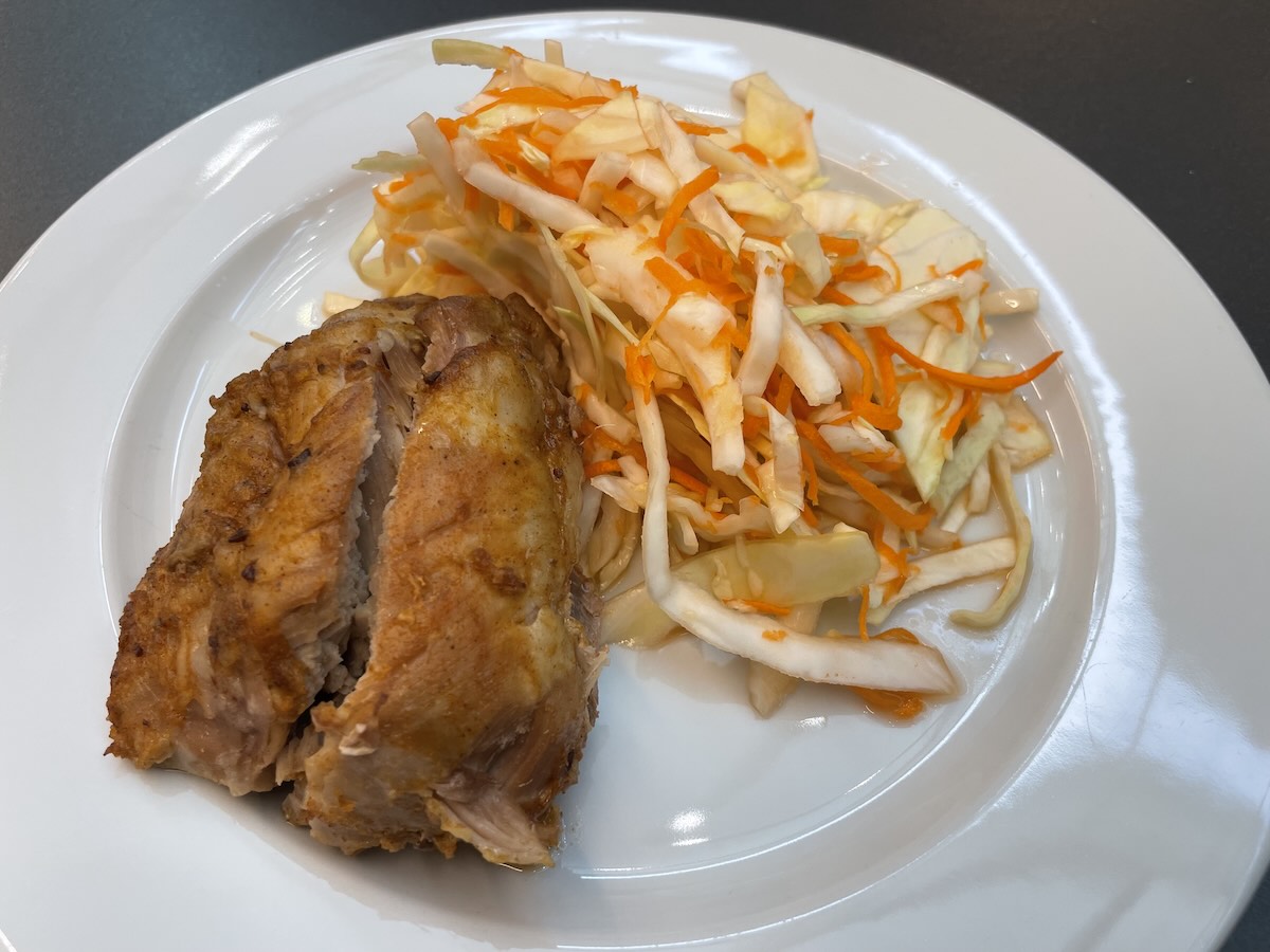 Pečené morčacie stehno podávané s kapustovým šalátom na bielom tanieri