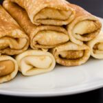 Prvá palacinka sa vždy zle podarí — zlatohnedé rolované palacinky na bielom tanieri