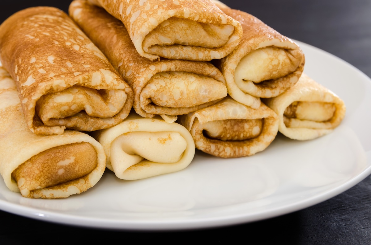 Prvá palacinka sa vždy zle podarí — zlatohnedé rolované palacinky na bielom tanieri