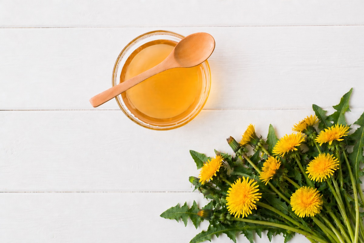 Domáci púpavový sirup s púpavami na svetlom podklade.