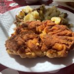 Rezne z vykostených kuracích stehien na bielom tanieri s opečenými zemiakmi