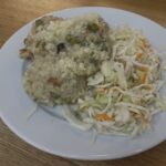 Krémové rizoto s kuracím mäsom a hráškom posypané parmezánom na bielom tanieri