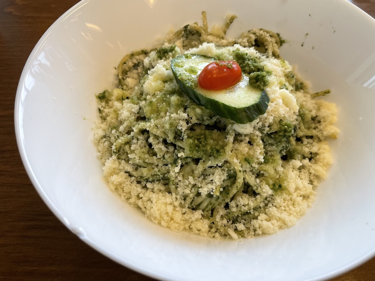 Špagety s pestom, špenátom a špargľou posypané parmezánom v bielej miske