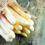 Čerstvá biela špargľa zviazaná jutovým motúzom na drevenom povrchu