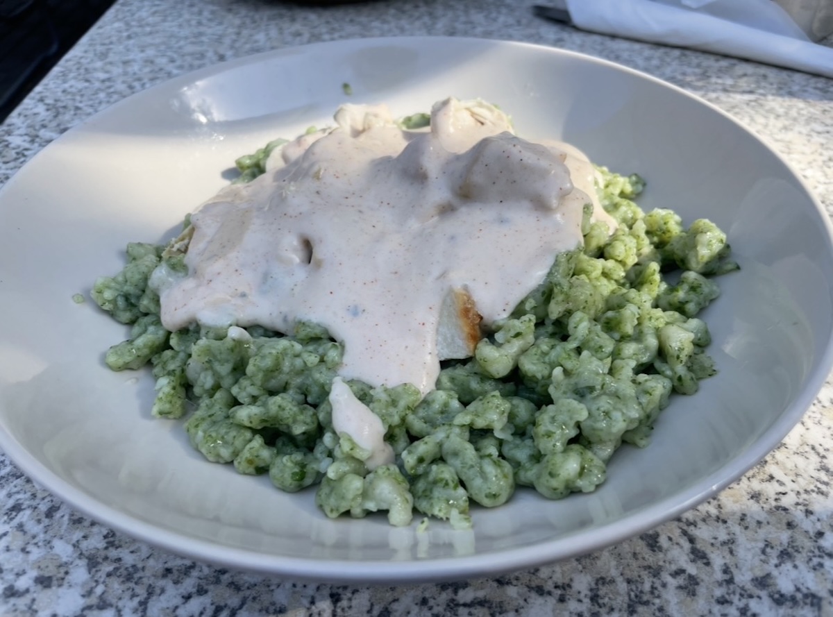 Špenátové halušky so syrovou omáčkou a kuracím mäsom v bielom hlbokom tanieri