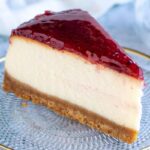Jednoduchý tvarohový cheesecake bez pečenia Kúsok tvarohového cheesecaku bez pečenia s jahodovou omáčkou na sušienkovom spodku na sklenenom tanieri