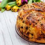 Veľkonočný mazanec s hrozienkami a orechmi na tanieri s tulipánmi