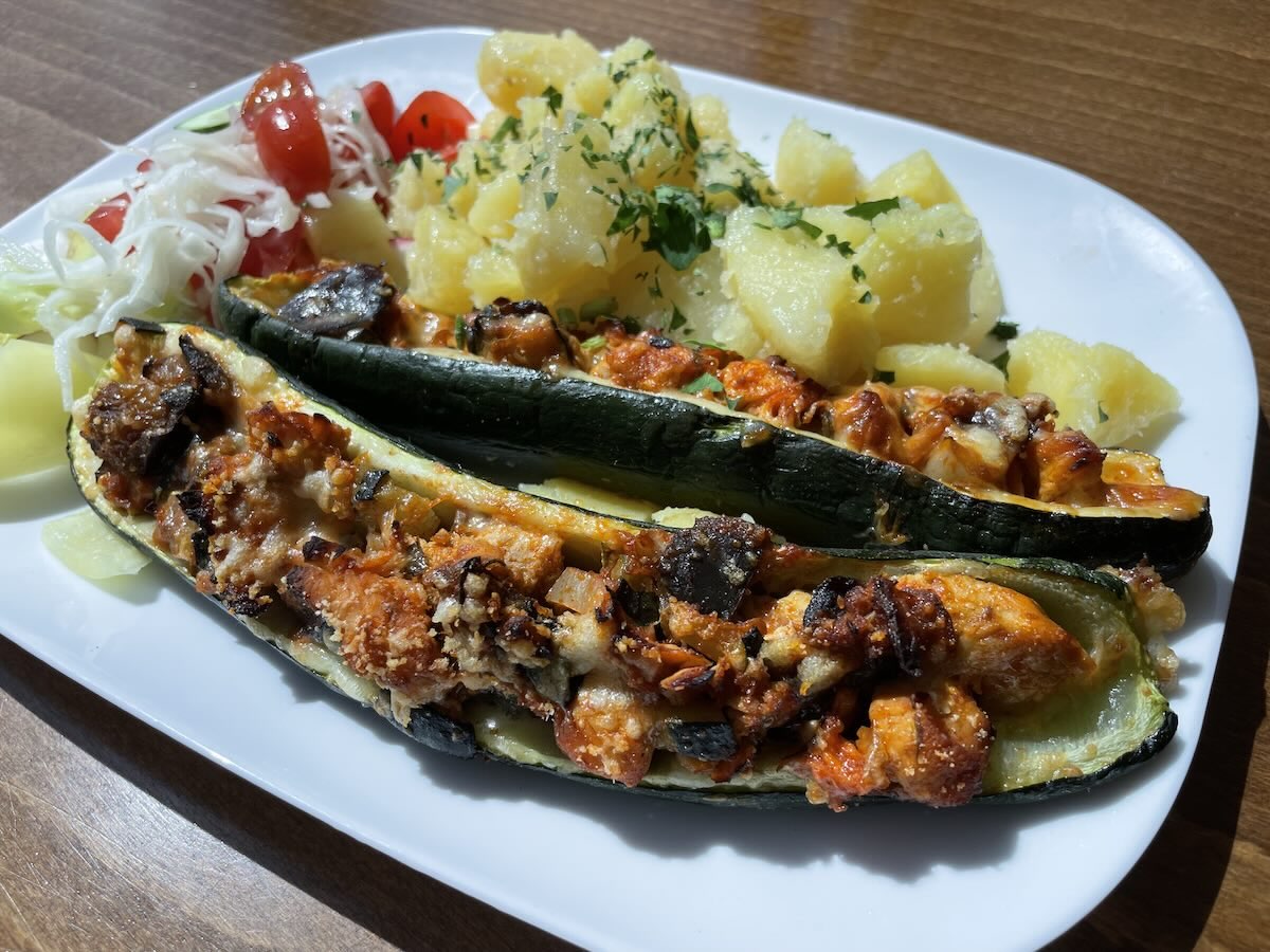 Zapekaná cuketa plnená kuracím mäsom a syrom podávaná so zemiakmi a šalátom