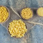 Rôzne druhy suchých cestovín v miskách – fusilli, penne, mušľovité a drobné cestoviny