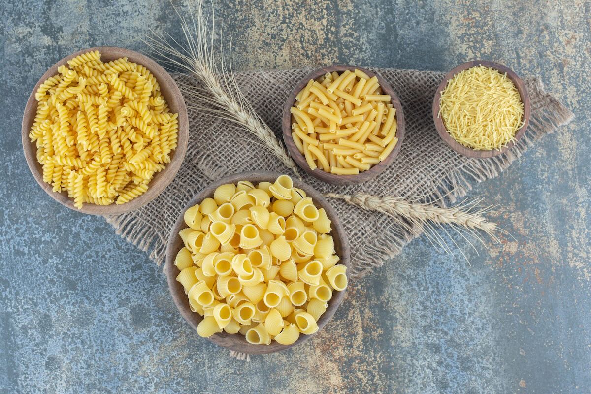 Rôzne druhy suchých cestovín v miskách – fusilli, penne, mušľovité a drobné cestoviny