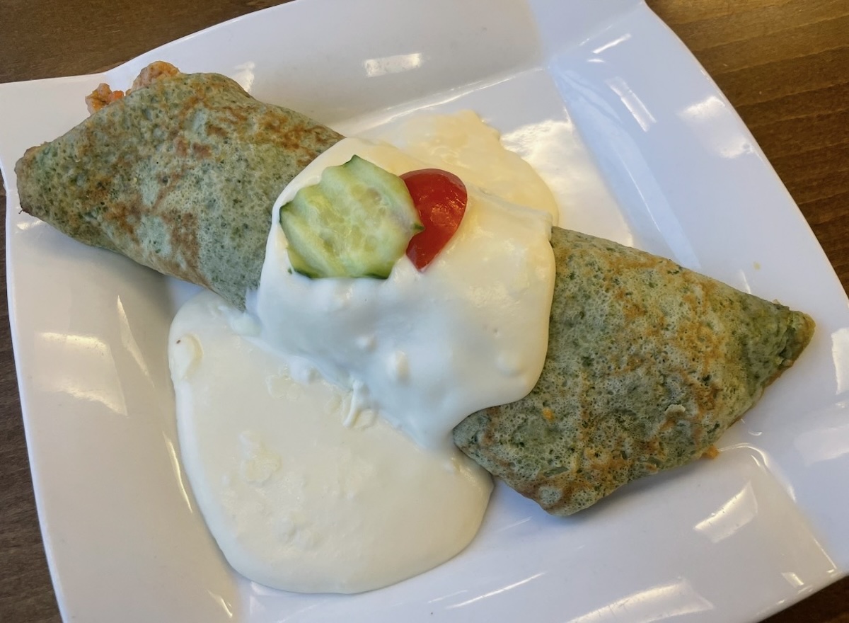 Špenátové palacinky so smotanovou omáčkou, uhorkou a cherry paradajkou na tanieri
