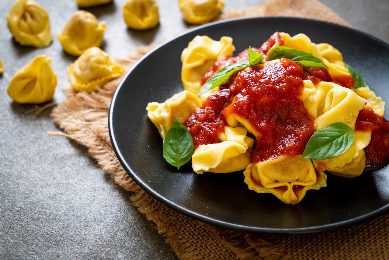 Tortellini s paradajkovou omáčkou a čerstvou bazalkou na čiernom tanieri