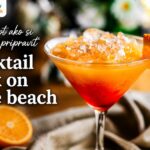 Ako pripraviť koktail Sex on the Beach doma Koktail Sex on the Beach v pohári s ľadom, pomarančom, červenou a oranžovou vrstvou, logom ReceptyRychlo.sk a nápisom Recept ako si doma pripraviť koktail Sex on the Beach